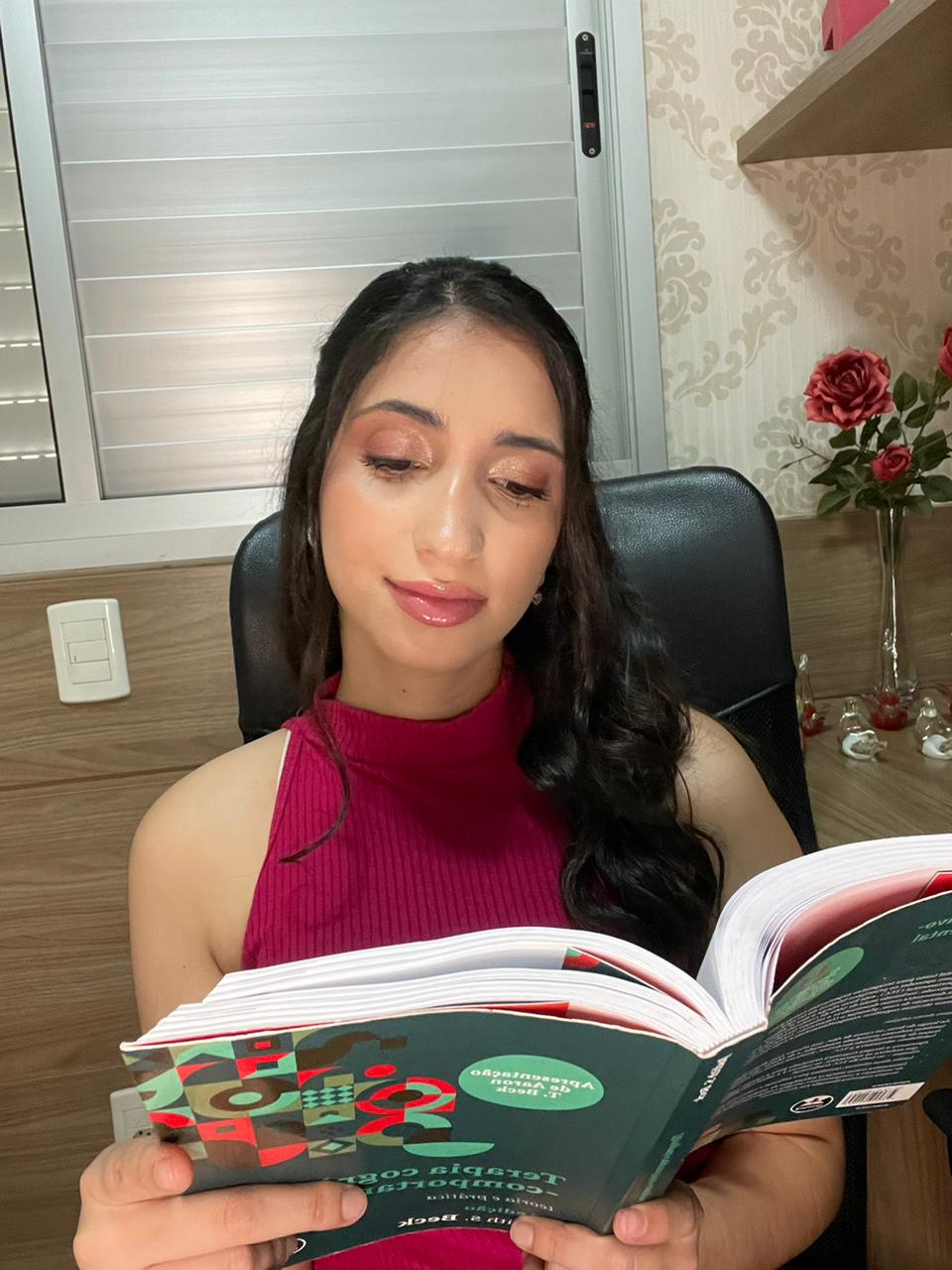 Kamilly Arantes lendo um livro de psicologia em seu consultório